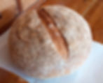crusty white polish sourdough loaf on a sheet of paper on a wooden unit
