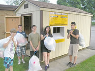 kid volunteers in front of new clothing shed