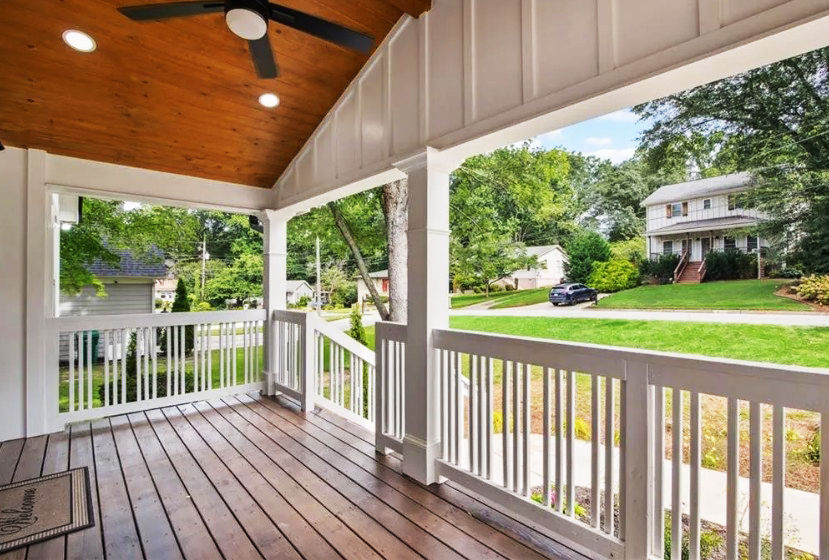 Covered front porch of a renovated Smyrna, Georgia home featuring wood decking, decorative columns, a vaulted wood ceiling, and inviting outdoor living space.