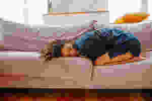 women lying on a couch in blue pajamas with belly pains