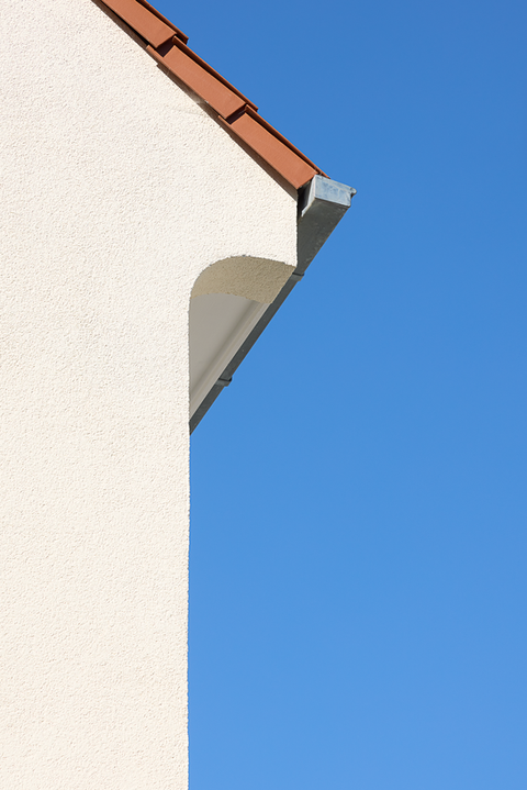 Dachrinne am Haus vor blauem Himmel