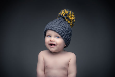 cute little toddler wearing a grey and yellow bobble hat 