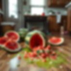 Watermelons sliced open in a kitchen, spilling juice and chunks on the wooden floor. Bright, messy scene with a cozy background.