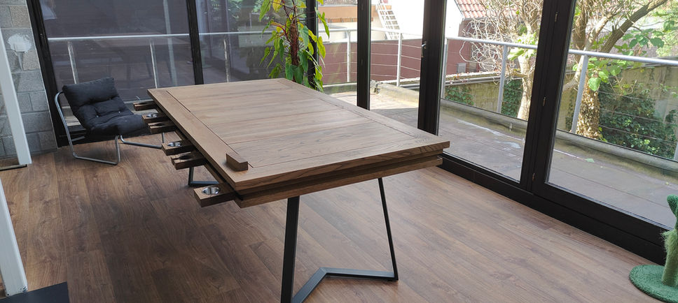 Houten eettafel met metalen poten, met stoel, en groene buiten uitzicht.