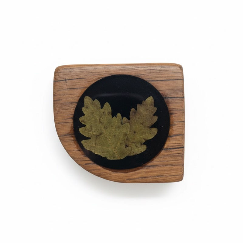 Thumbnail: Close-up of a preserved oak leaf motif embedded in black resin on wood.