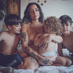Photo of a mother and her 3 children one of them breastfeeding