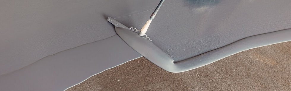 A person coating a floor with a thick, grey coating