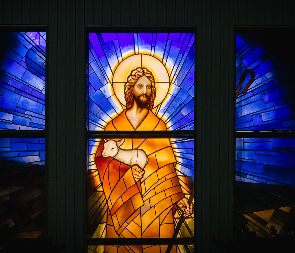 Stained glass window showing Jesus holding a lamb in his arms.