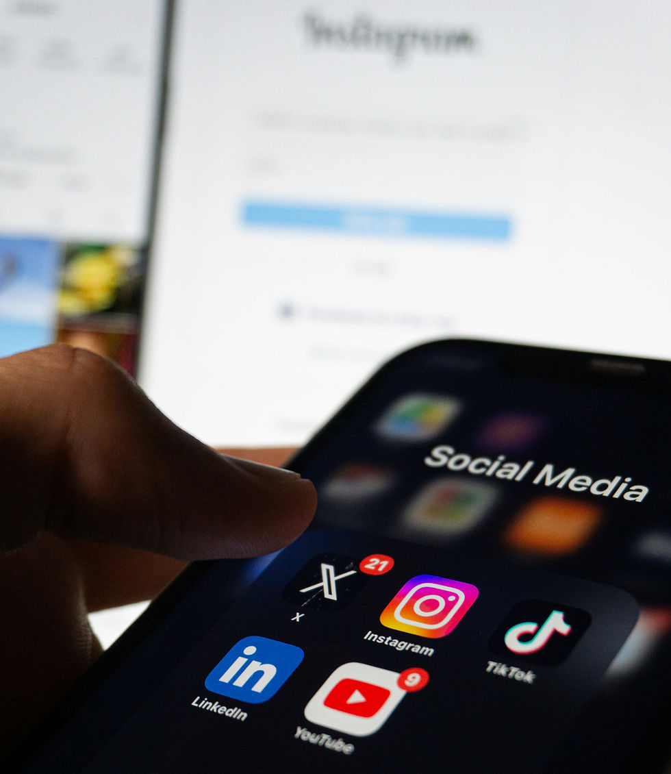 A close view of the Social Media folder open on a phone with Instagram open on a computer in the background.