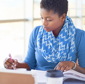 Student taking notes during her online A-level lesson.