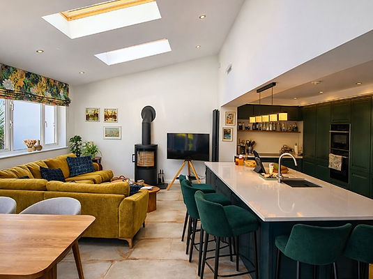 Open‑plan family room with skylights, mustard sofa and garden views in Donaghadee by GT Building Design