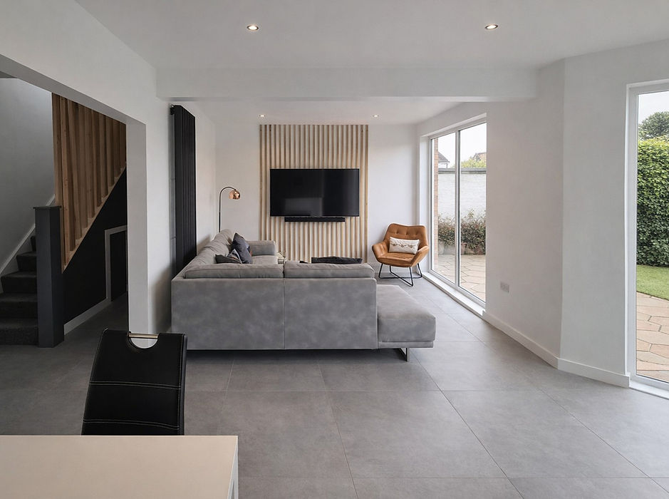 Modern living room interior with grey sofa, tan armchair, and glazed doors by GT Building Design, Donaghadee