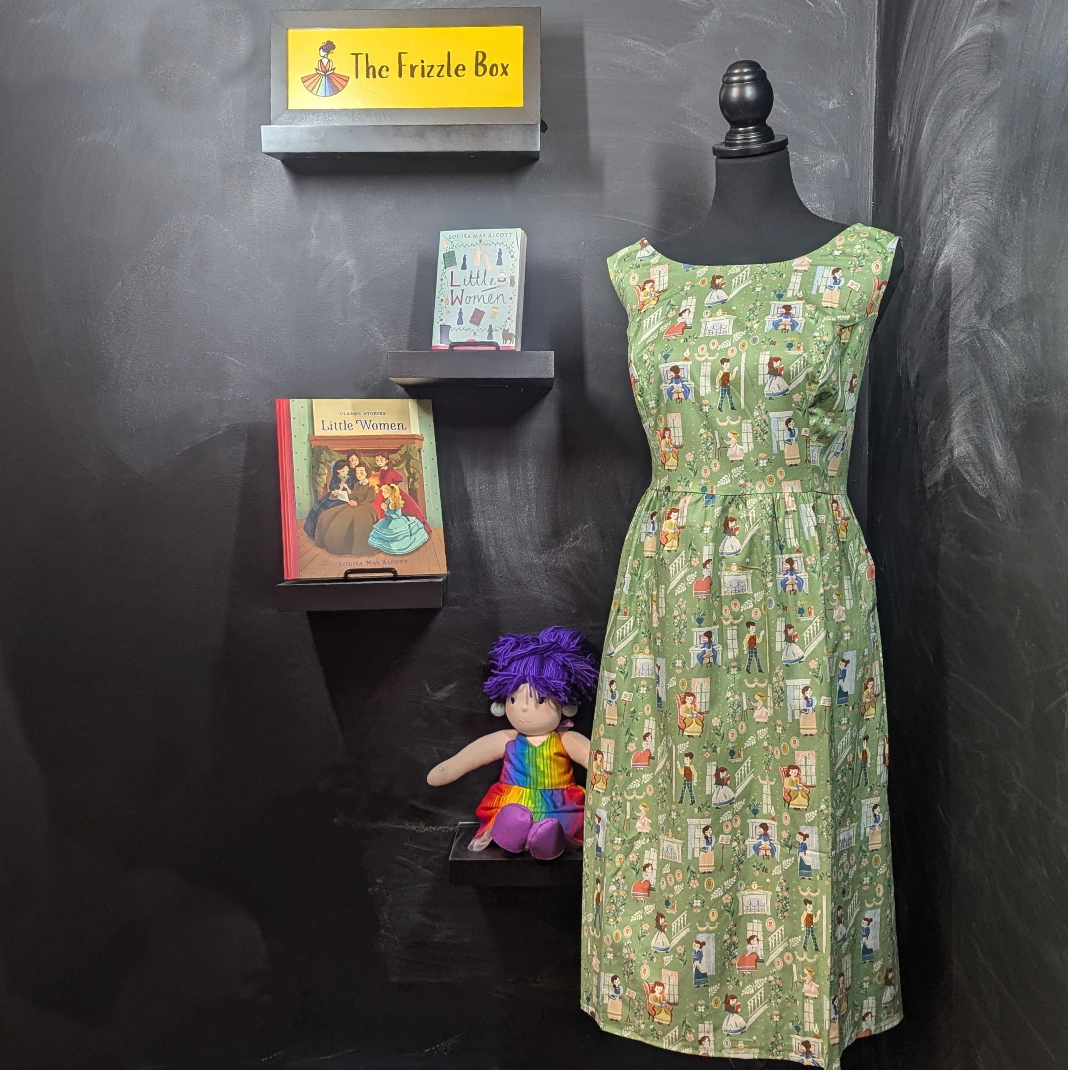 Picture of Little Women print dress, the Little Women chapter book, a children's picture book adapting Little Women, and the Frizzle Box logo and mascot Mini Frizzle doll (not for sale). 