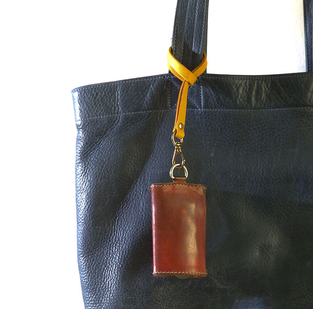 A yellow Radiana strap is attached to a blue leather tote bag