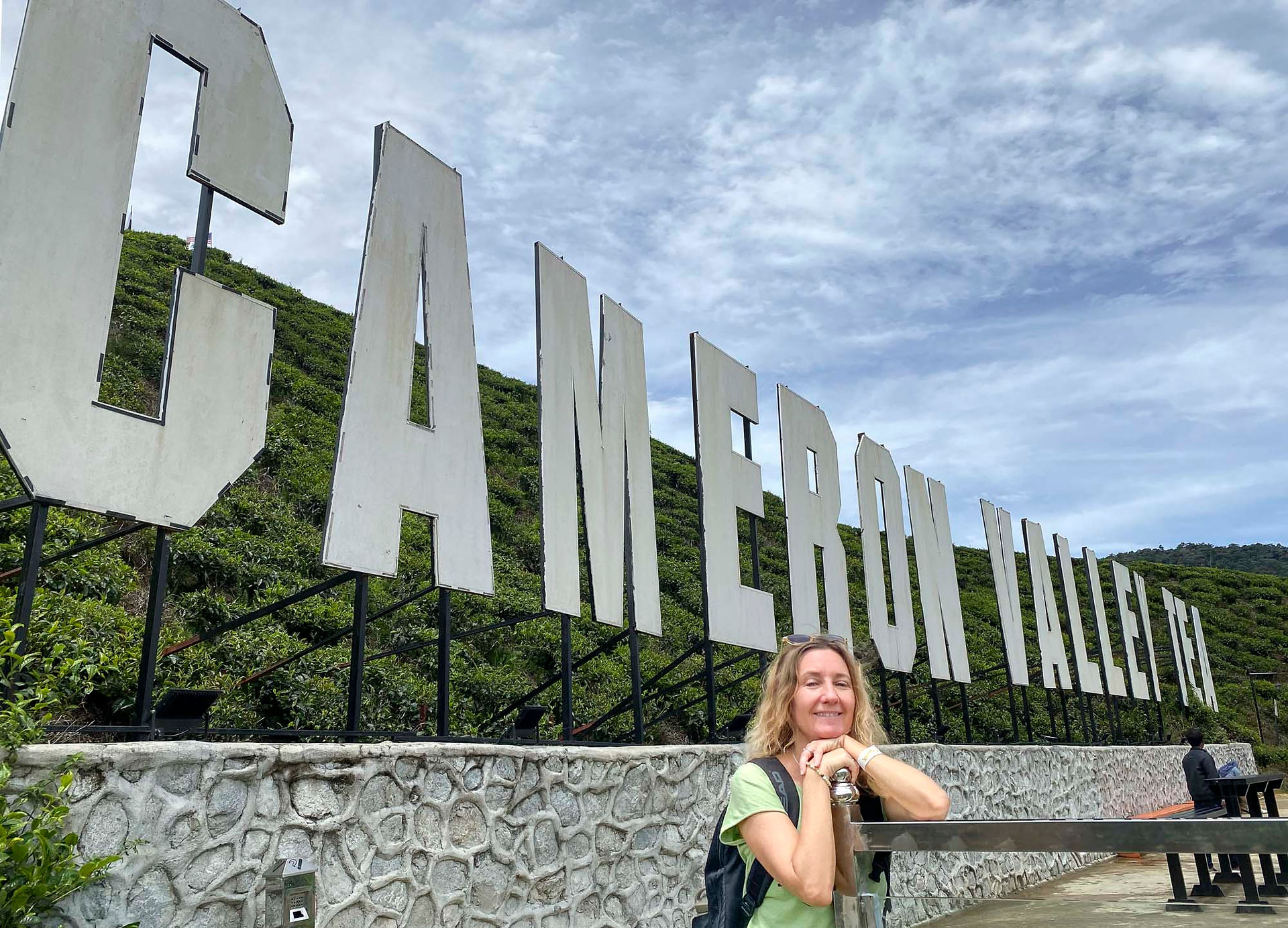 Woman standing in front of the Cameron Valley Tea sign in Tanah Rata