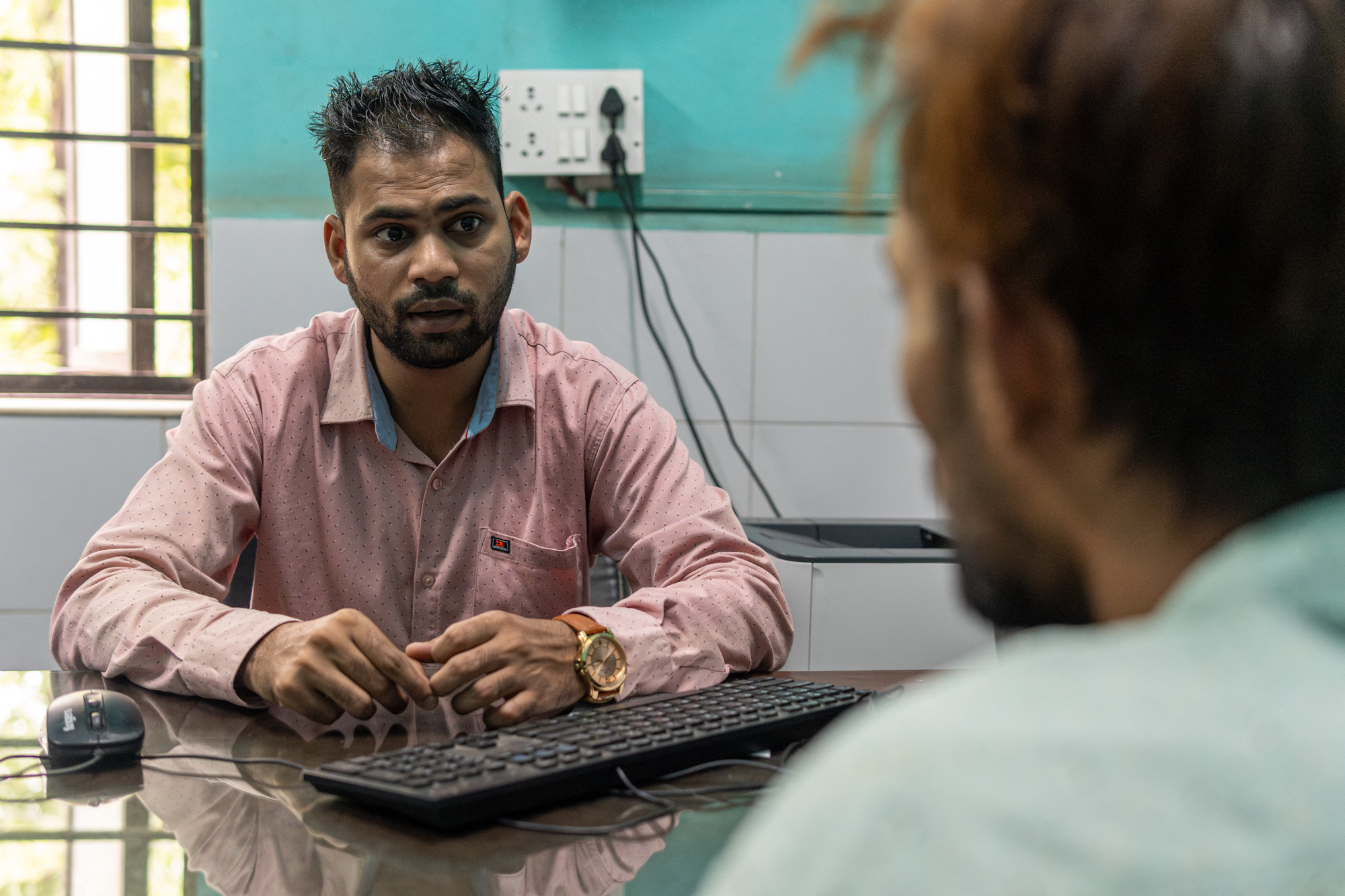 The data manager at an OST centre speaks with a client across his desk