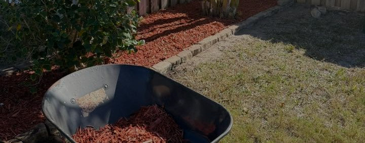 Wheelbarrow with red mulch for dependable quality lawn care.
