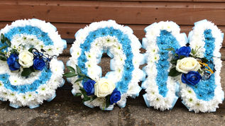 Floral name bouquet sign spelling Son White Based with Pale Blue Centre . Blue and White Roses as embellishment
