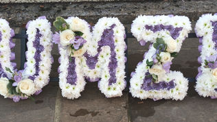 Floral name bouquet sign spelling Mumzie White Base with Purple Centre highlighted with White Roses