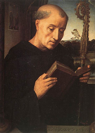 A medieval image of St Benedictine dressed in black looking at a book that he is holding in his hands.