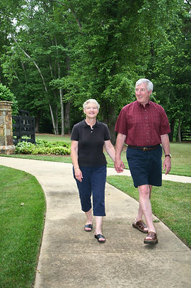 An elderly man and woman walking outside in a retirement community.jpeg