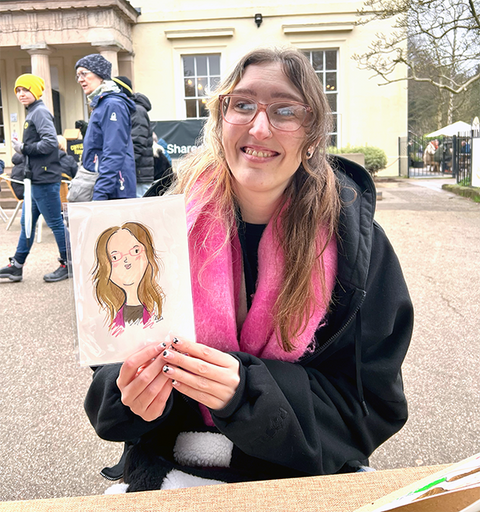 Smiling woman holding a drawing of herself