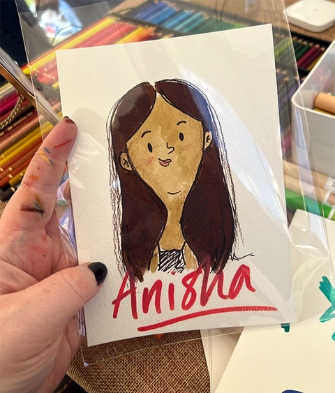 Hand holding drawing of woman with text Anisha