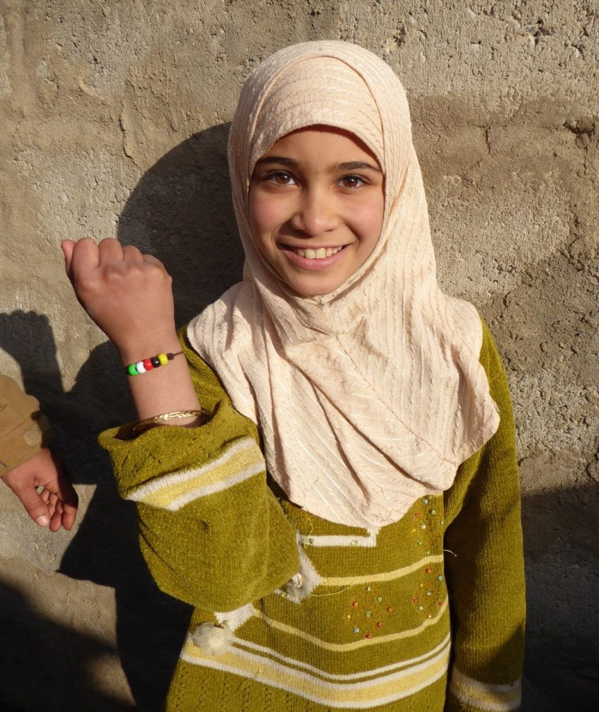 Young girl newly freed from ISIS at a children’s program with a bracelet that symbolizes God’s love