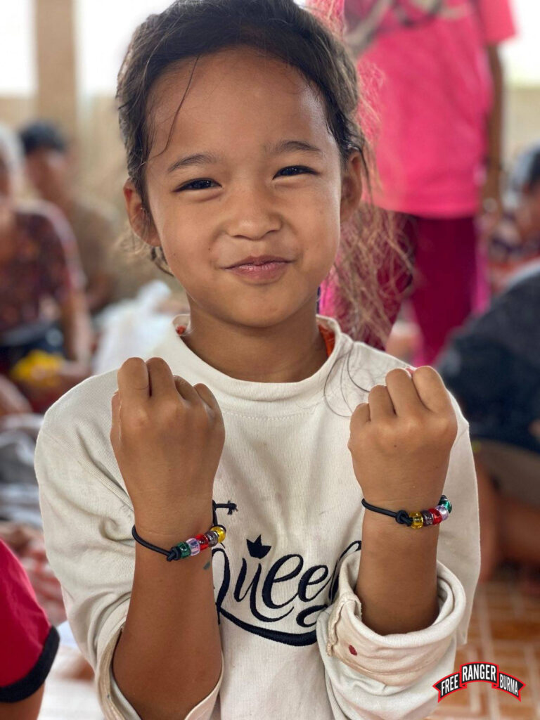 A young girl smiles, showing off her GLC bracelets.