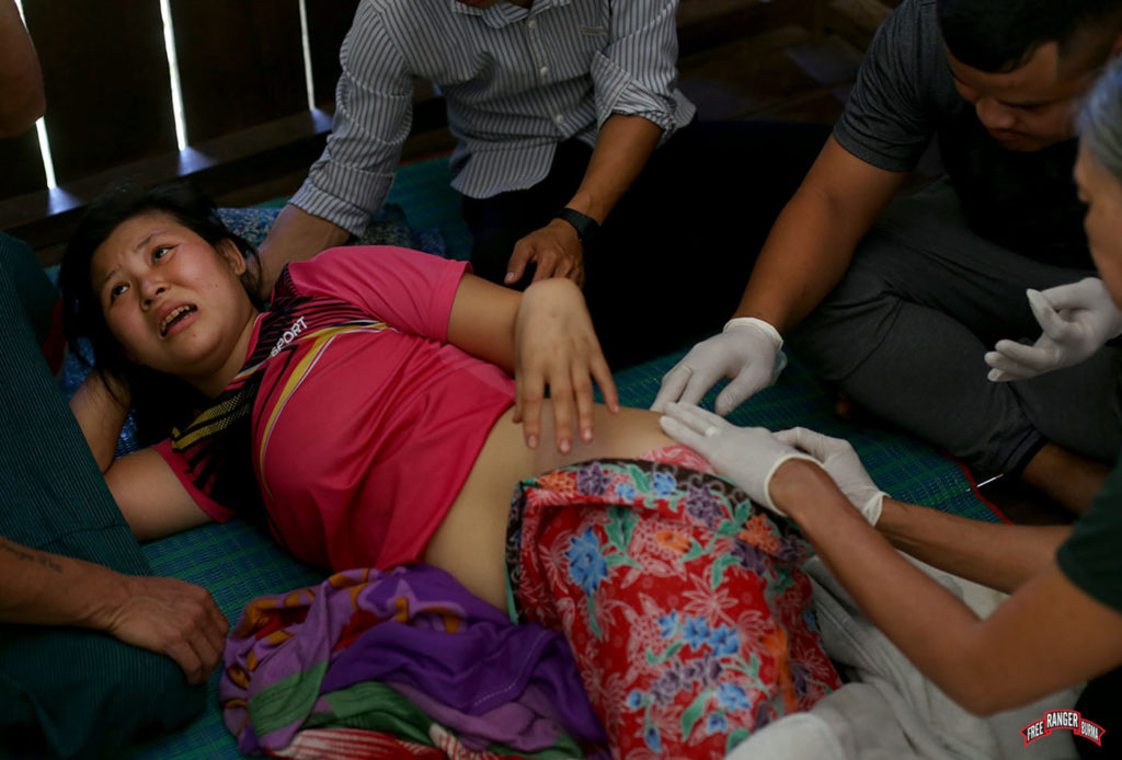 Assessing Na Day Mu's wounds from the bomb shrapnel.