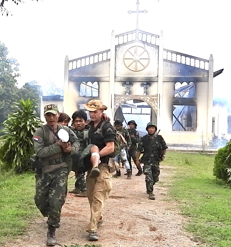 David and team carry 16 year old landmine victim in front of burning church, Karenni State