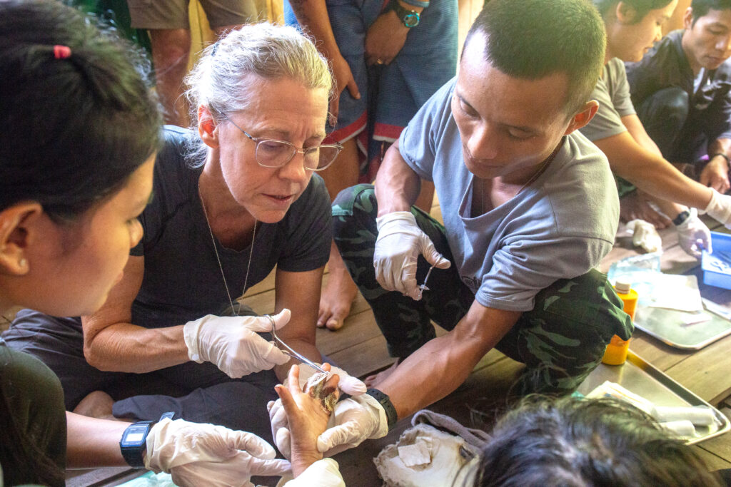 Dr. Dale Woodall helps JSMK students remove bandages from a girl whose hand was burned.