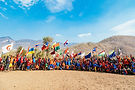 A group of children from Burma hold flags and jump up and down