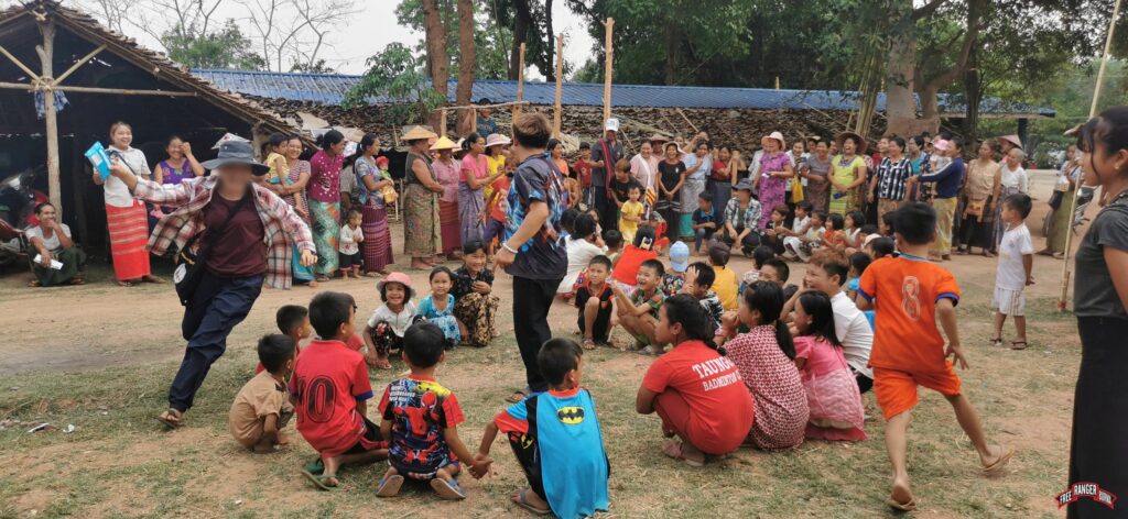Rangers and villagers laugh and play games with children during a GLC program.