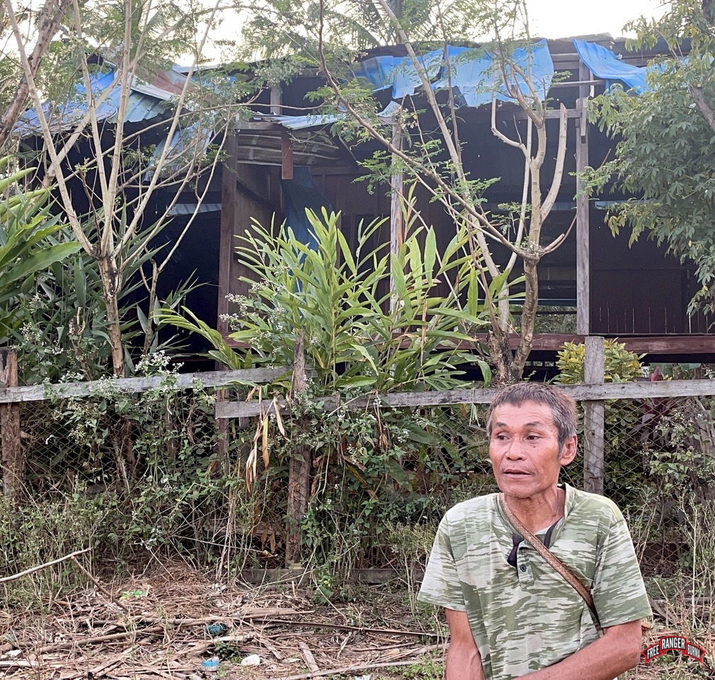 The Head man of Mae Kaw Law stands in front of the home where three people were injured by an earlier bombing.