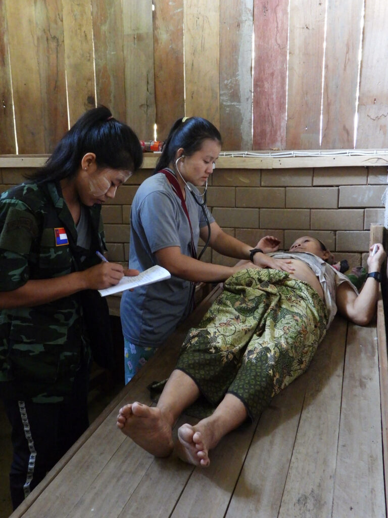 Naw Say Moo Paw, in gray shirt, with a patient.