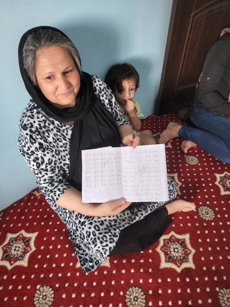  A woman happily learning to write in her native language: Dari.