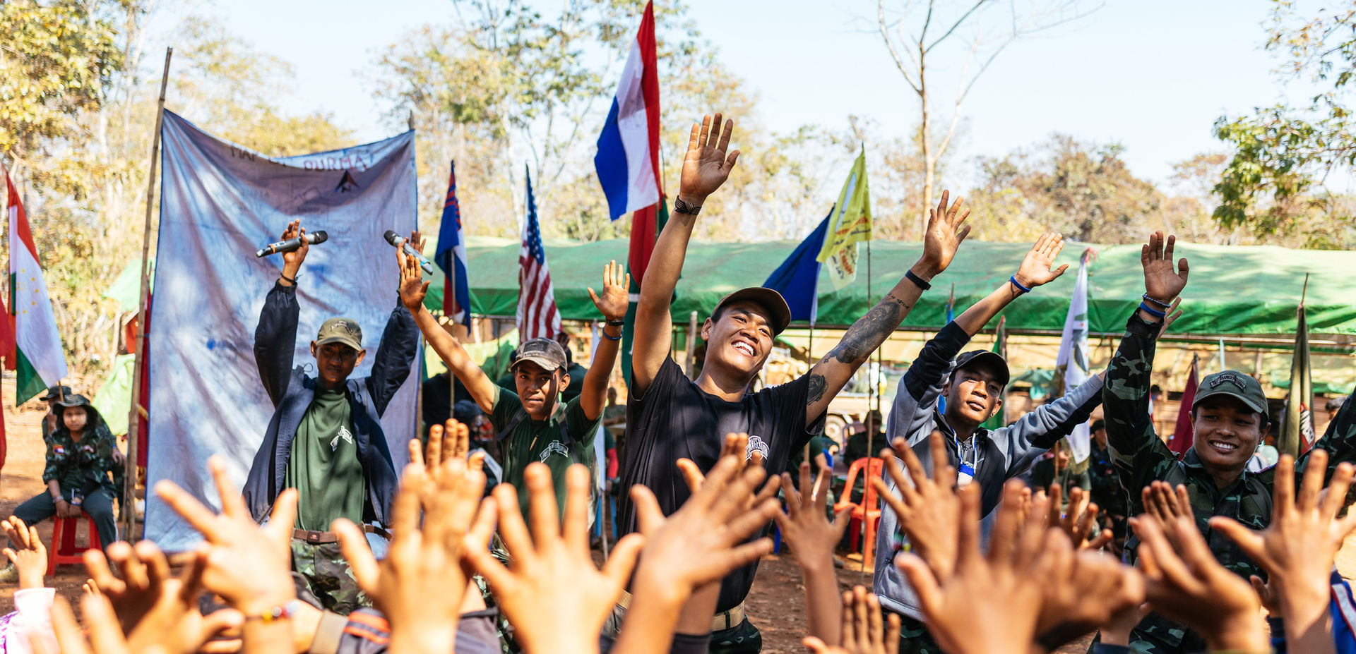 A humanitarian aid worker raises his hands while leading a group of children in song