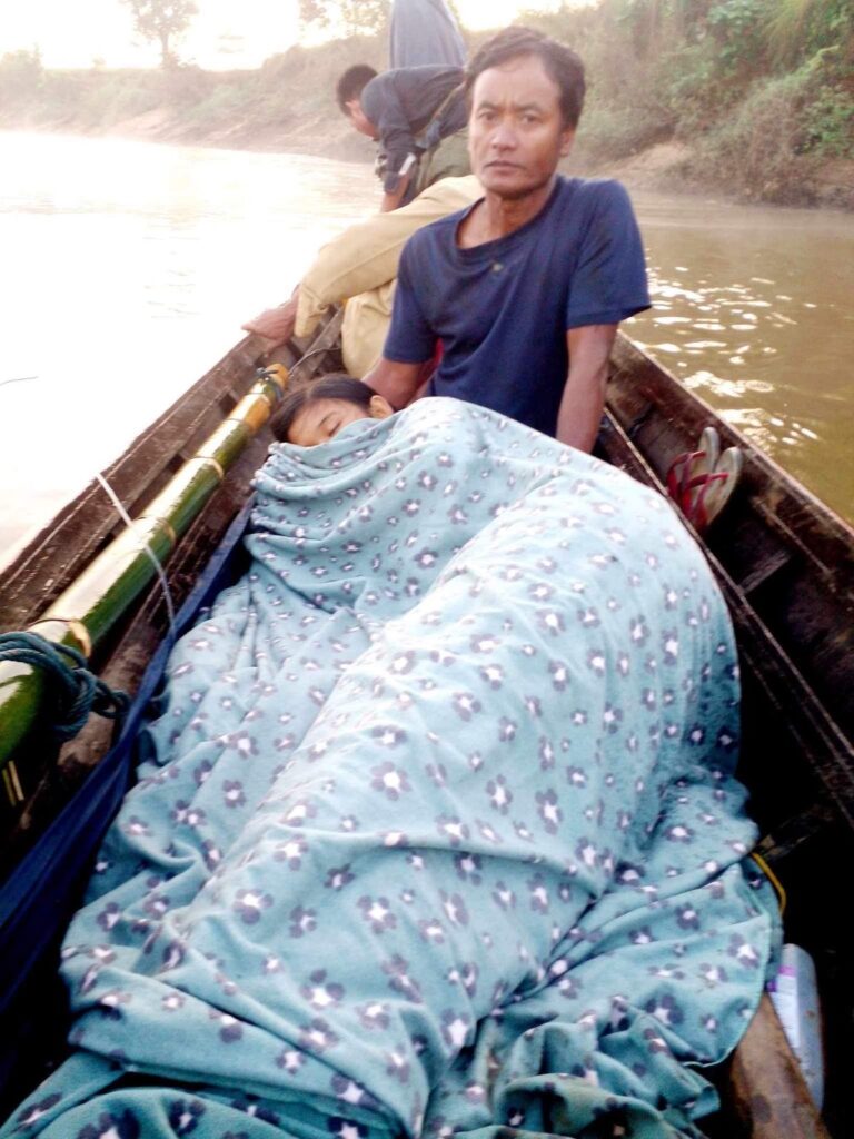 A man takes his 18-year-old daughter to a medical clinic after her foot was injured by Burma Army artillery.