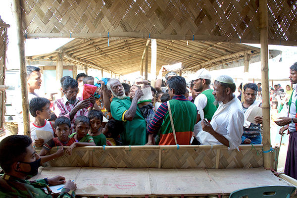 Rohingya men jostle for a spot at the front of a line during a distribution in one of the many refugee camps.