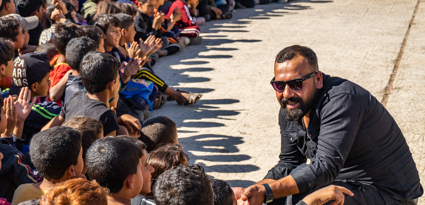 A man from Syria helps children during a kids program