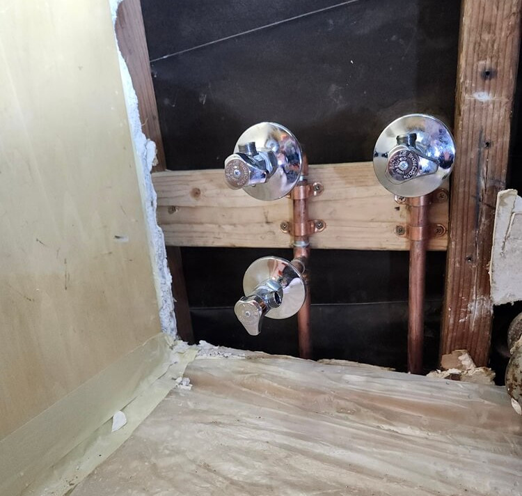 Open wall copper repipe with new angle stops installed beneath a kitchen sink during a whole-home repiping project in Altadena.