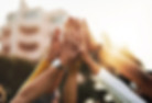 Group of people high fiving, celebrating a shared accomplishment together outdoors.