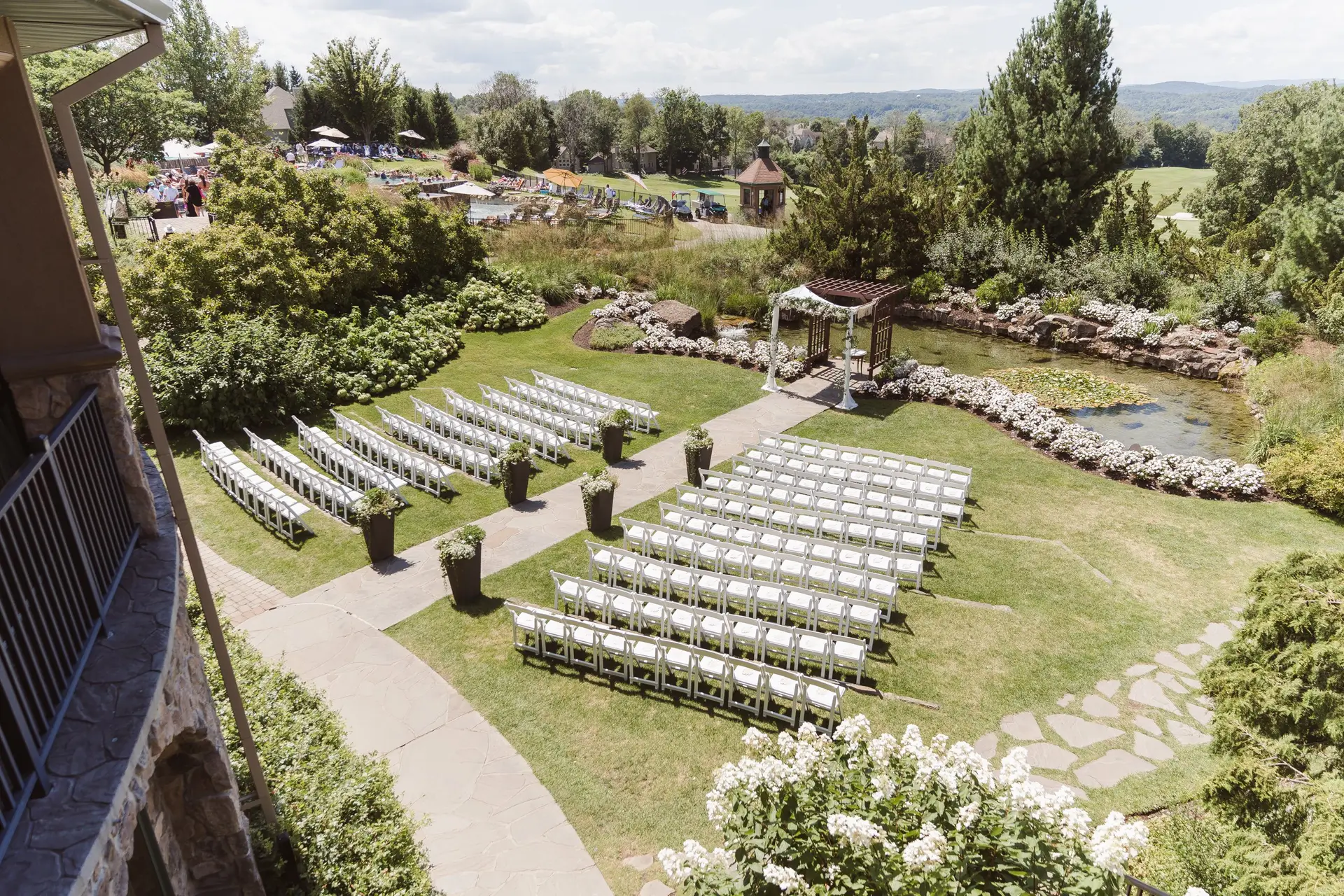 Aerial ceremony setup with white seats, trees, and grass.