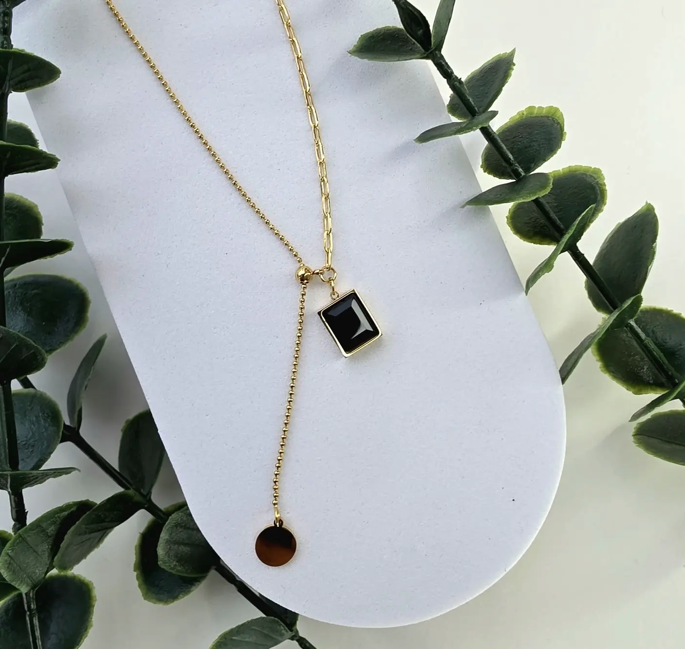 gros plan sur un collier à chaîne ajustable avec un pendentif rectangulaire en pierre noire