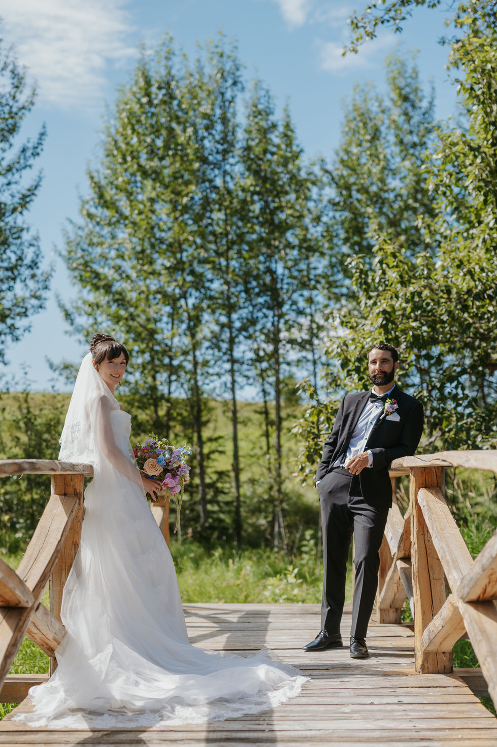 Bride and groom walking on a wooden bridge during pre-ceremony wedding portraits.