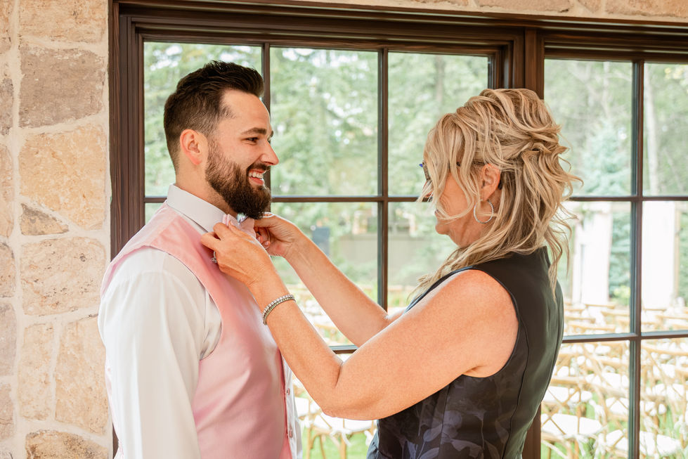 Groom having his pink bow tie adjusted before his Edmonton backyard wedding ceremony.
