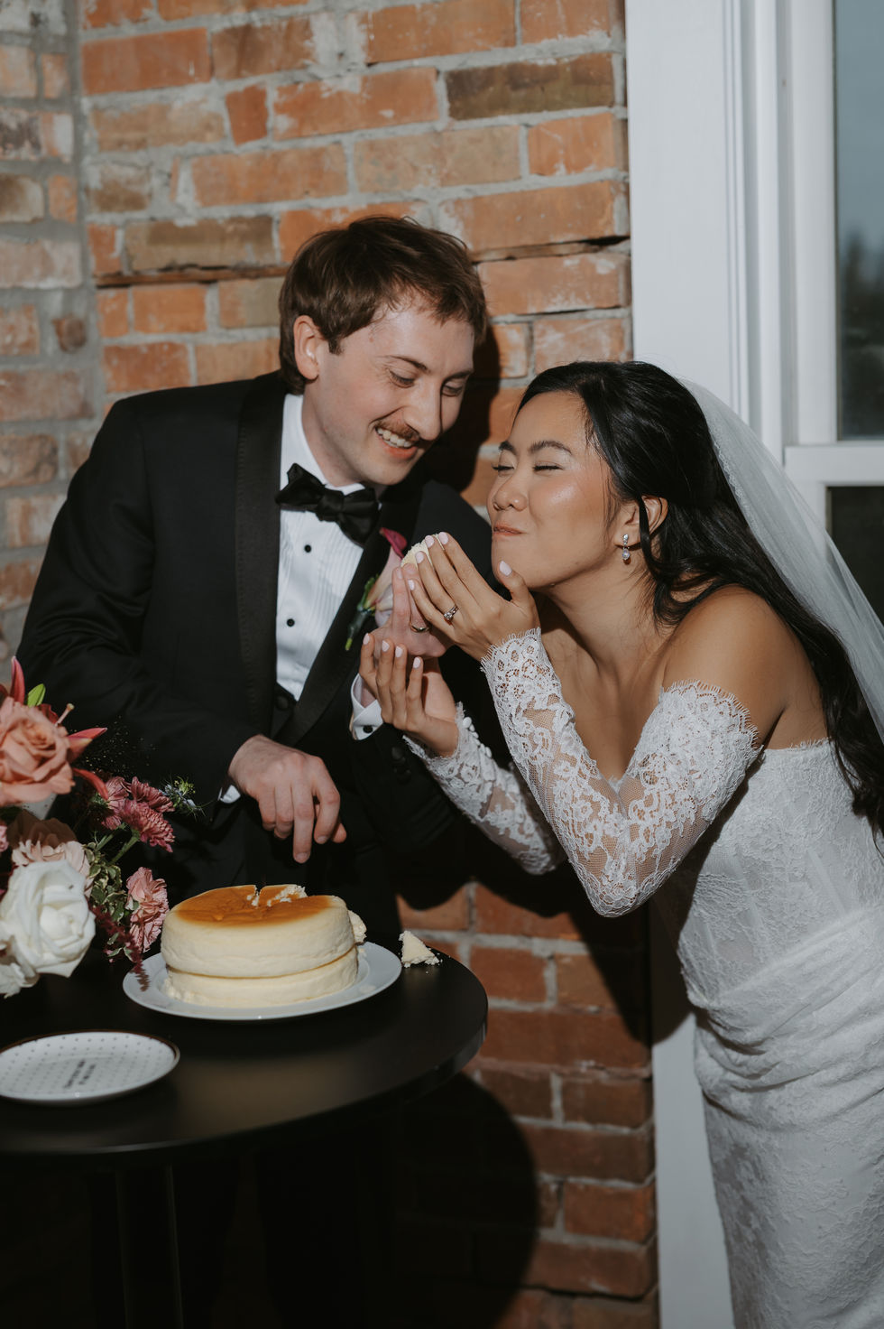 Bride and groom laughing together over dessert at their Edmonton wedding reception.