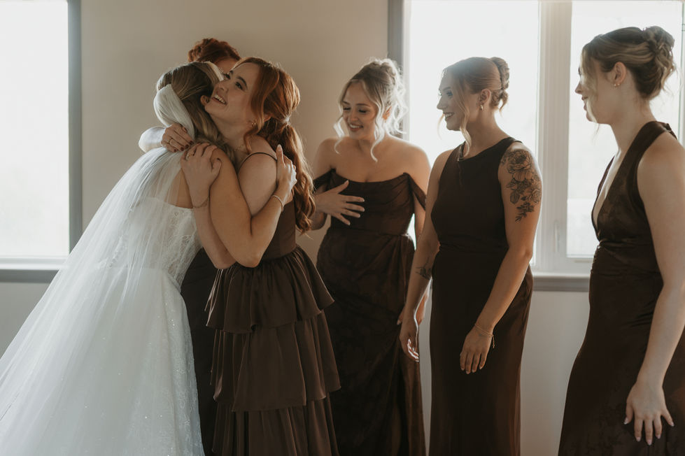 Bride hugging a bridesmaid while getting ready for her woodland wedding at The Valley.