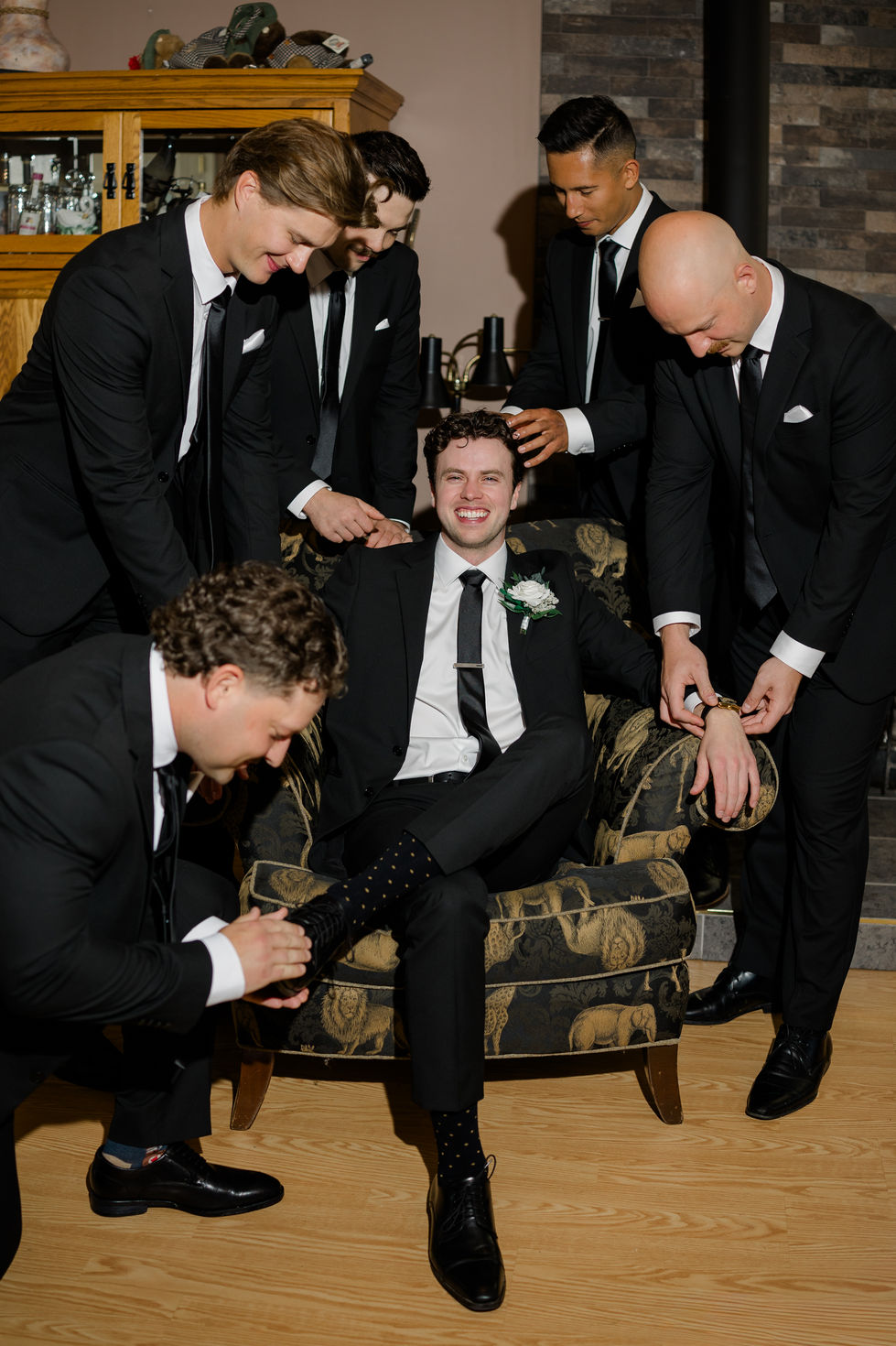 Groom and groomsmen in black suits getting ready before a wedding at The Valley near Edmonton.